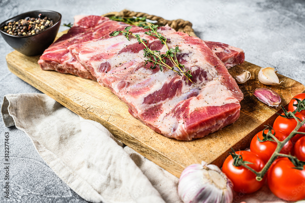 Fresh raw pork ribs with rosemary, pepper and garlic. Farm organic meat. Gray background. Top view