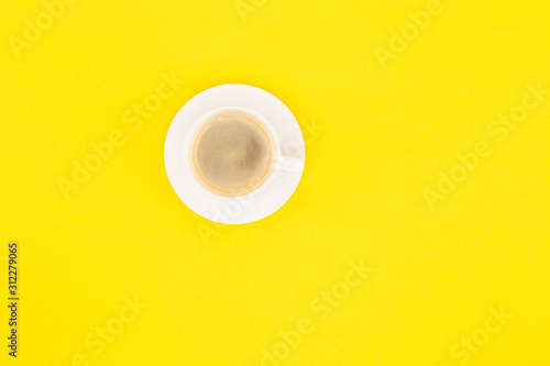 top view of coffee with foam in cup on saucer isolated on yellow