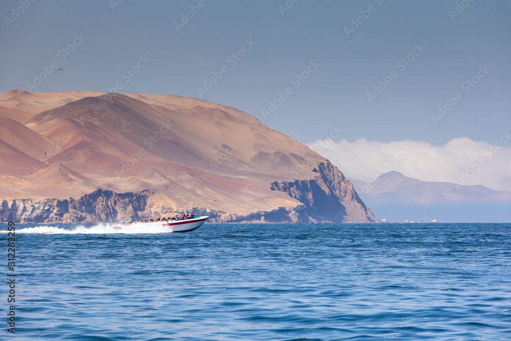 A speed boat carries tourists on an excursion to the island of Ballestas, the Ica region, Peru. Copy paste.