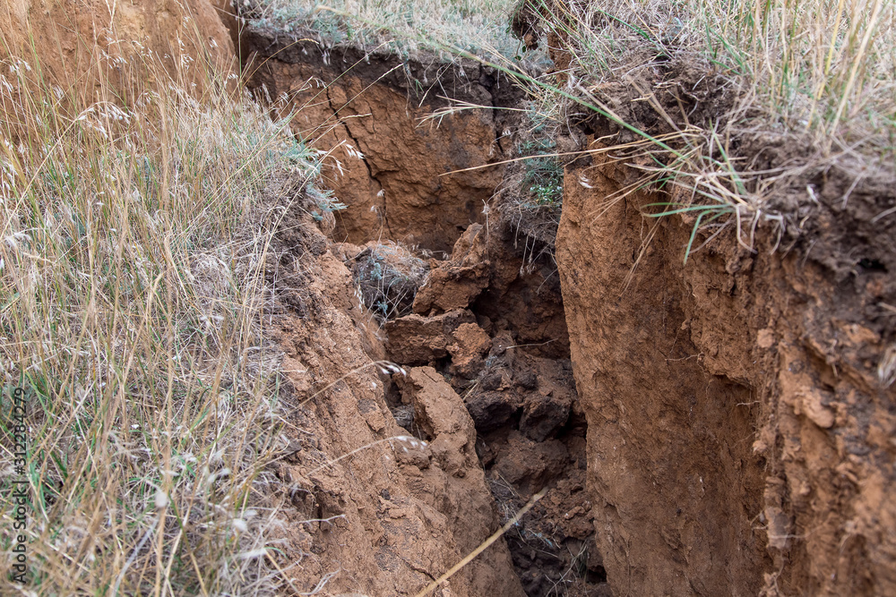 Fototapeta premium ecological disaster landslide of clay soil after an earthquake, a close up of earth cracks.