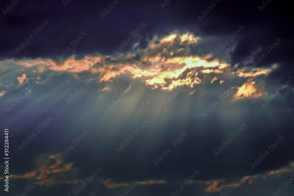 dark thunderclouds with cases of the sun. Rays of light against a background of dark blue clouds in the evening