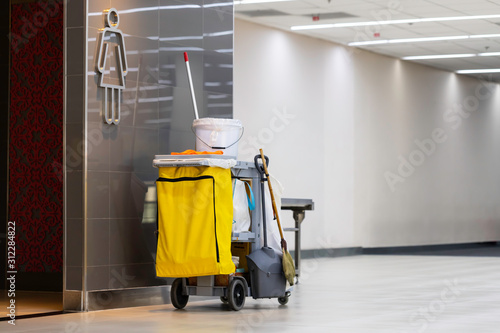 janitorial car preparing for cleaning in front of toilets.