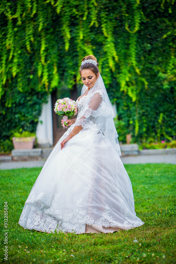 Young bride wearing gorgeous wedding dress, playing with veil. plays a wedding dress. Dress develops in the wind. Happy bride in a wedding dress is spinning.