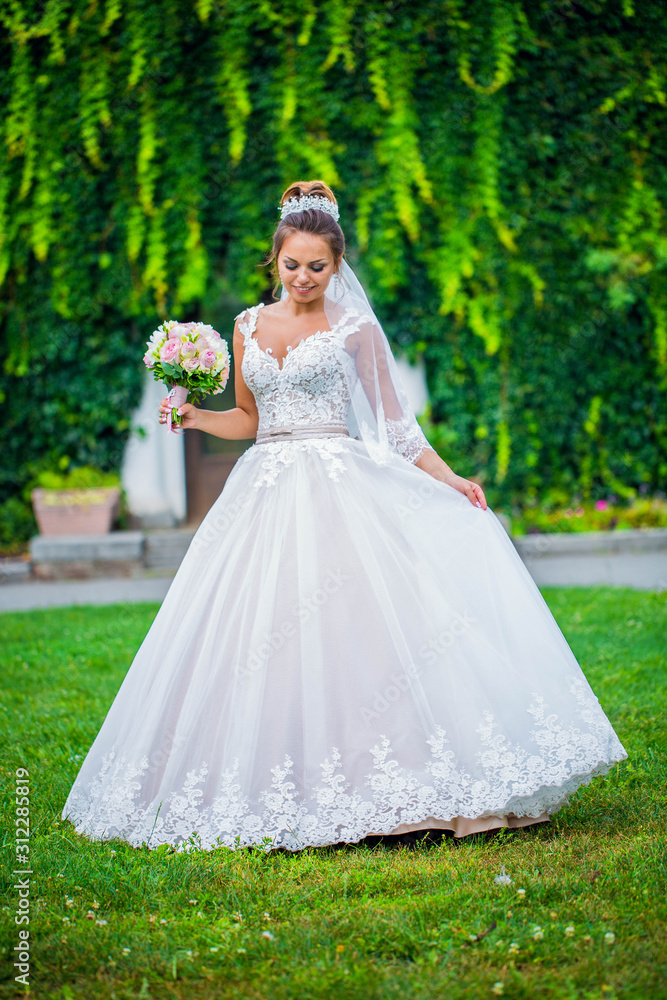 Young bride wearing gorgeous wedding dress, playing with veil. plays a wedding dress. Dress develops in the wind. Happy bride in a wedding dress is spinning.