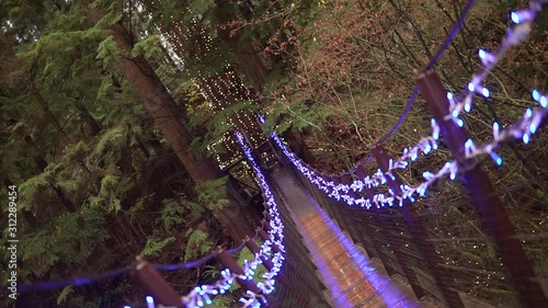 This was taken at a higher frame rate and has been converted to a slow motion video clip. Slow motion barrel shot of a suspension bridge covered in Christmas lights. photo