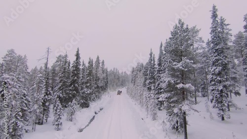 Drone flying towards cars stuck in a cross country road covered in snow during mid winter solstice. photo