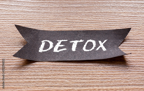 Detox word written on Black papper with wooden background