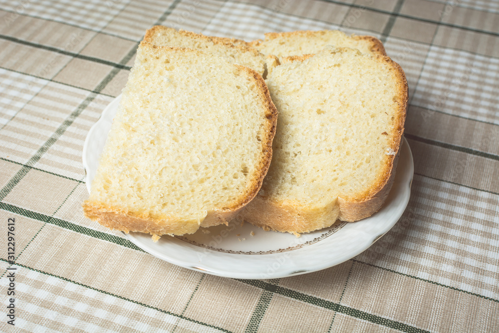 Sliced pieces of white bread in plate on kitchen table.