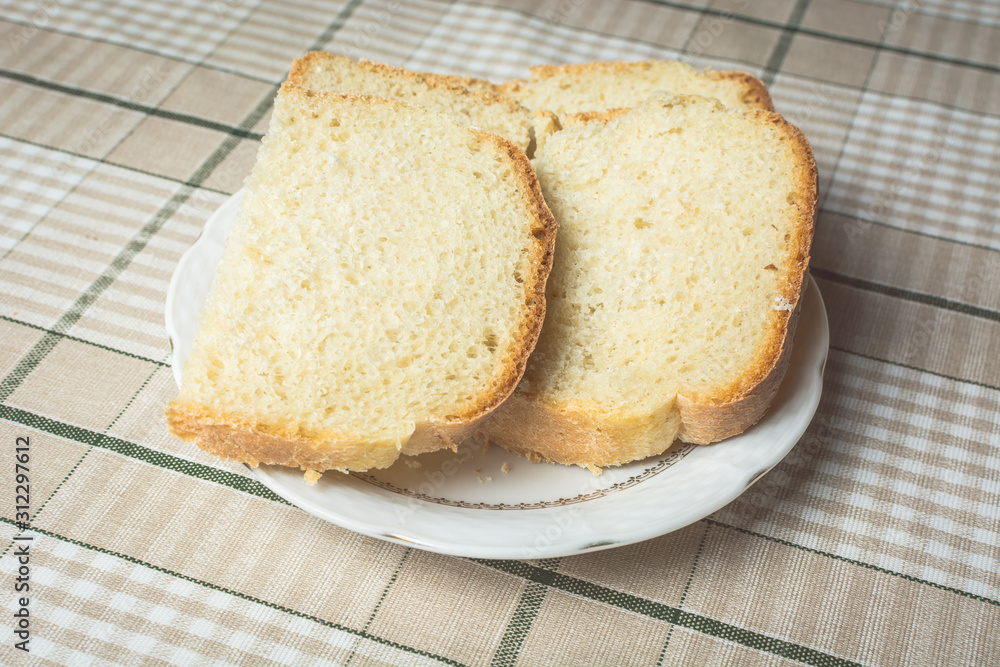 Sliced pieces of white bread in plate on kitchen table. Sliced pieces of white bread in plate on kitchen table.