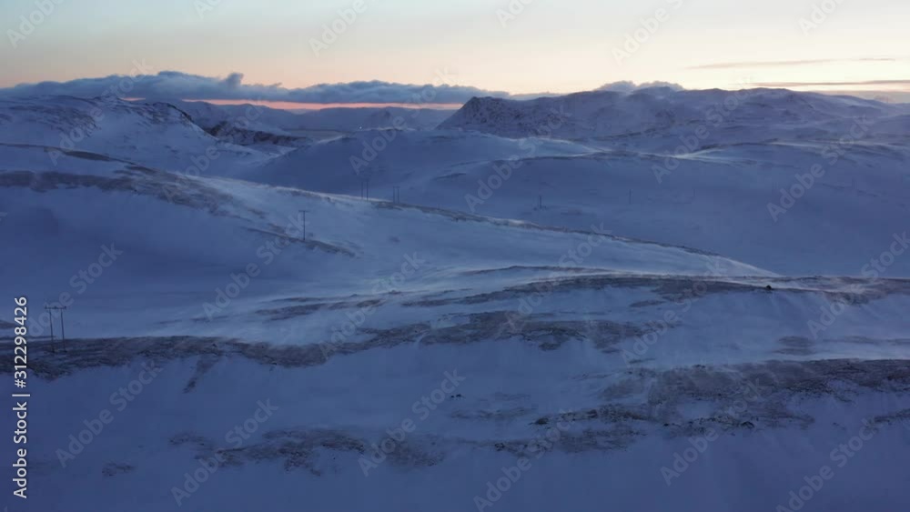 A windy frozen tundra with utility poles during a midwinter solstice day. Aerial shot. A windy frozen tundra with utility poles during a midwinter solstice day. Aerial shot.