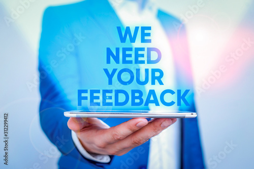 Writing note showing We Need Your Feedback. Business concept for criticism given to say can be done improvement Man in the blue suite and white shirt holds mobile phone in the hand