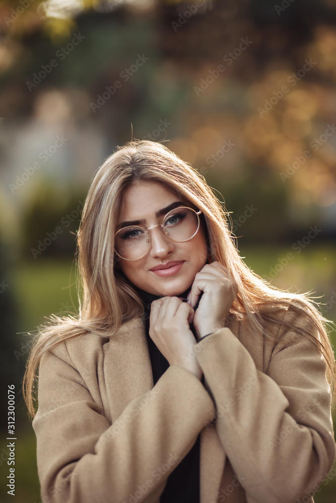 Autumn portrait. Cheerful stylish woman in image glasses and coat in the park Autumn portrait. Cheerful stylish woman in image glasses and coat in the park