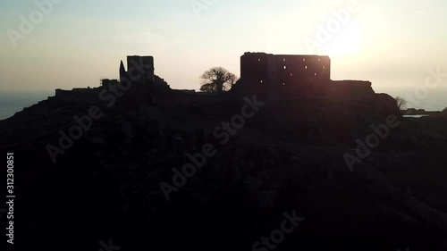 Parallax view of secluded, northern, midieval stone fortification castle at sunset photo