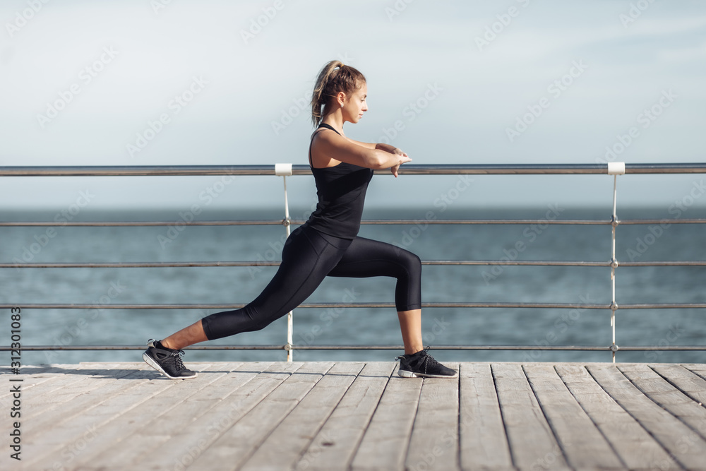 Warm up before training. Slim young woman with perfect body doing aerobic exercise on the beach on a bright sunny day. Warm up before training. Slim young woman with perfect body doing aerobic exercise on the beach on a bright sunny day.