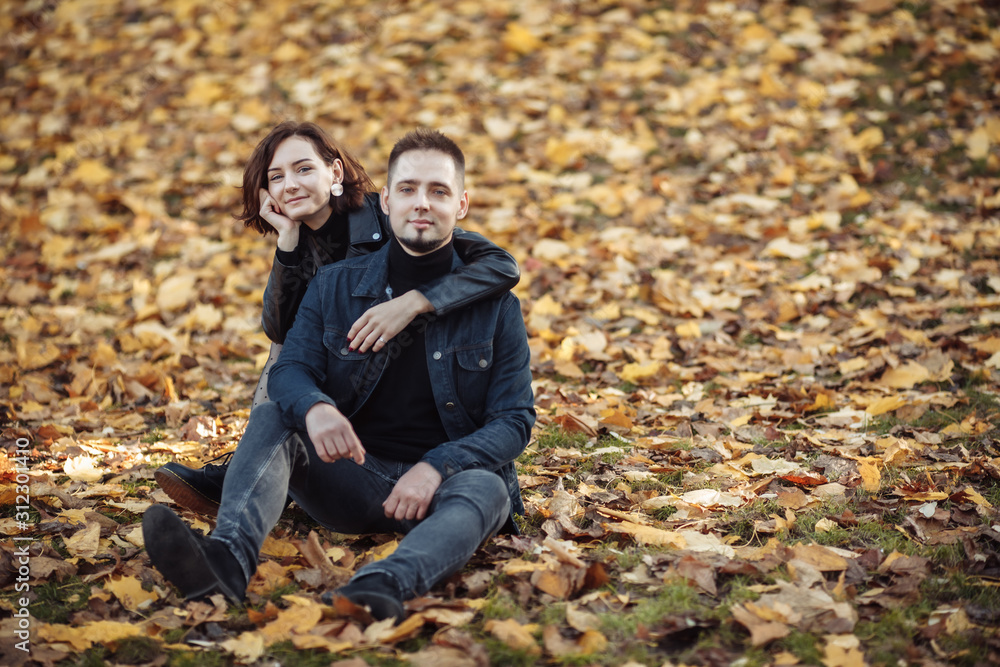 Young hugging couple of lovers on a blurry background of fallen autumn leaves in the park. Romantic, love concept