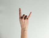 Female hand shows rock gesture on a white background