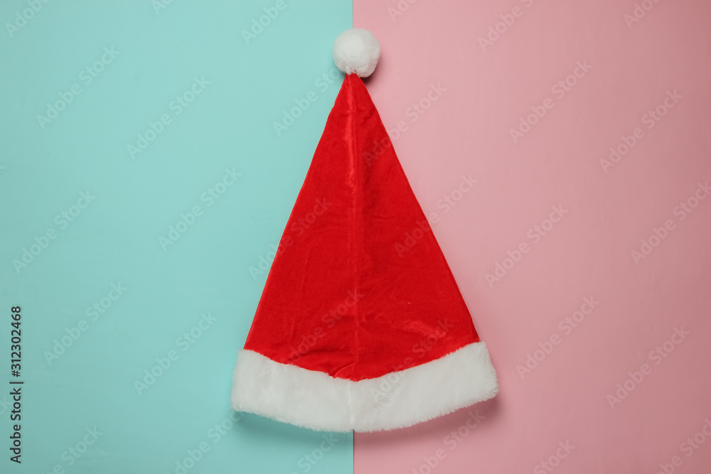 Santa hat on blue-pink pastel background. New Year, Christmas minimalistic concept. Top view, studio shot. Santa hat on blue-pink pastel background. New Year, Christmas minimalistic concept. Top view, studio shot.