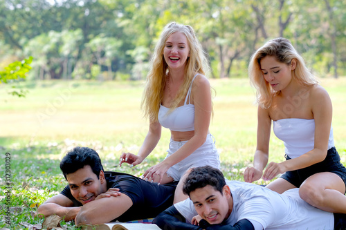 Two lovely teens massage to sport men in the garden with fun emotion.