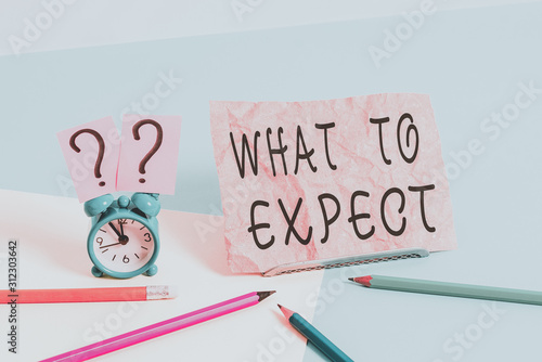 Conceptual hand writing showing What To Expect. Concept meaning Confusion about the belief of what will happen in future Mini size alarm clock beside stationary on pastel backdrop photo