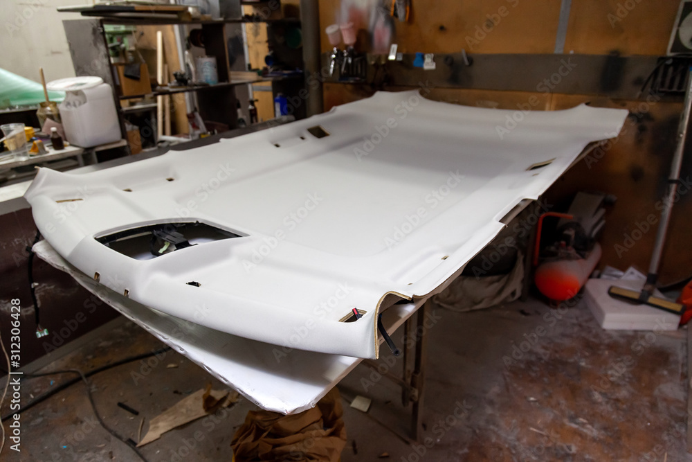 Finishing the gray ceiling from a car removed and disassembled for repair and hauling with new material after prolonged use or during tuning. Auto service industry. Finishing the gray ceiling from a car removed and disassembled for repair and hauling with new material after prolonged use or during tuning. Auto service industry.