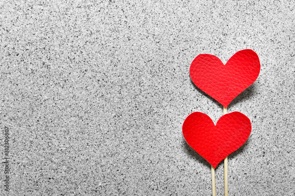 Two red fabric cloth hearts on wooden sticks on gray stone like texture background. Photo with copy blank space. Two red fabric cloth hearts on wooden sticks on gray stone like texture background. Photo with copy blank space.