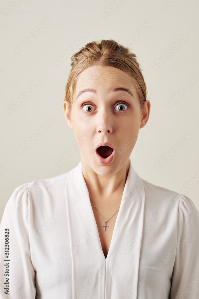 Portrait of shocked excited young businesswoman with wide eyes and mouth opened looking at camera Portrait of shocked excited young businesswoman with wide eyes and mouth opened looking at camera
