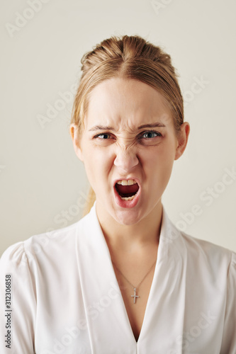 Portrait of angry shouting young businesswoman in white blouse