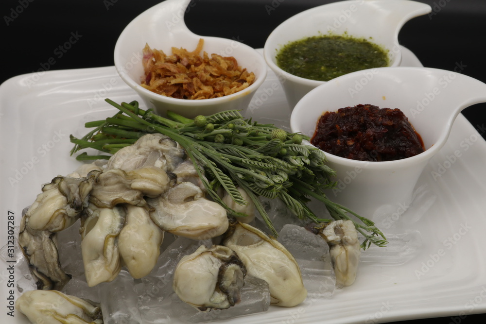 Fresh oyster with seafood sauce, chili paste and acacia on white plate Fresh oyster with seafood sauce, chili paste and acacia on white plate