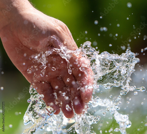 Hand of a man in the spray of water of the fountain