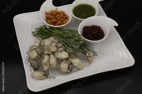 Fresh oyster with seafood sauce, chili paste and acacia on white plate