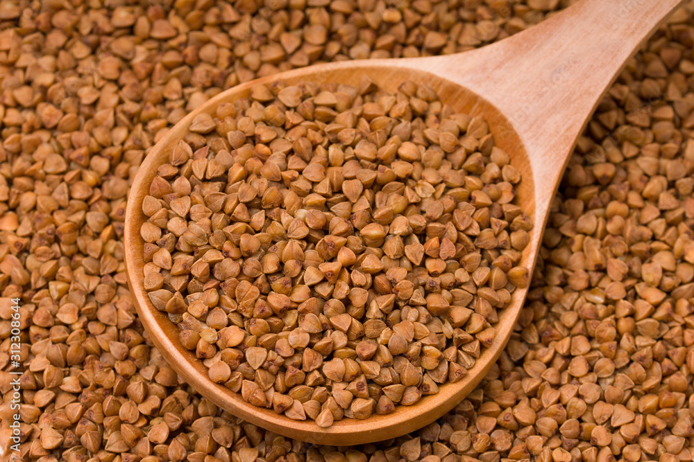 Raw buckwheat in a wooden spoon. healthy lifestyle, diet, weight loss, healthy food concept Raw buckwheat in a wooden spoon. healthy lifestyle, diet, weight loss, healthy food concept