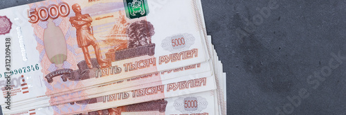 Big stack of Russian money banknotes of five thousand rubles lying on a grey cement background. photo