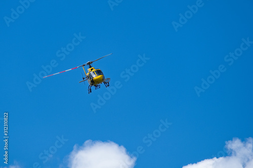 Elicottero giallo in volo su un cielo blu intenso con qualche nuvola. Copy space. Utilizzato per interventi di salvataggio in montagna