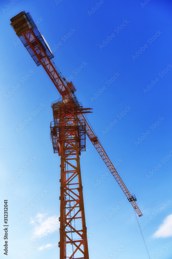 Yellow tower cranes at construction site. Construction site with tower cranes against blue sky. Crane and building construction site at sunset. Selected focus