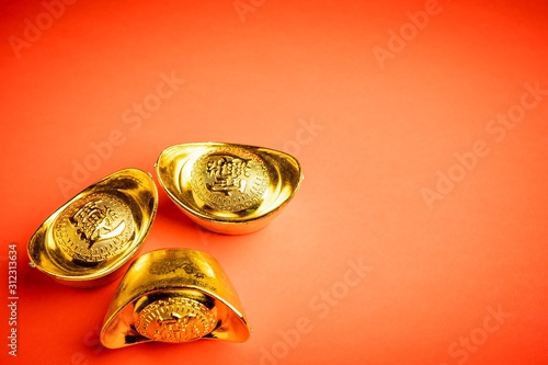 Chinese gold bars against red background. The wordings on bar is chinese words which means “bring in wealth and treasure”