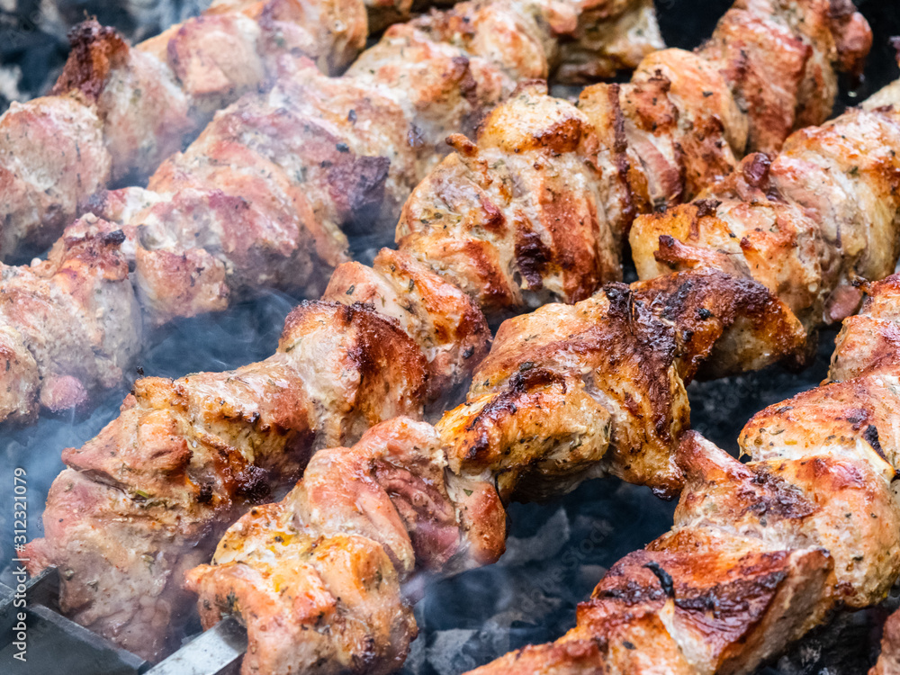 Frying pork on a skewer over a brazier. Turning meat over coals. Appetizing shish kebab.