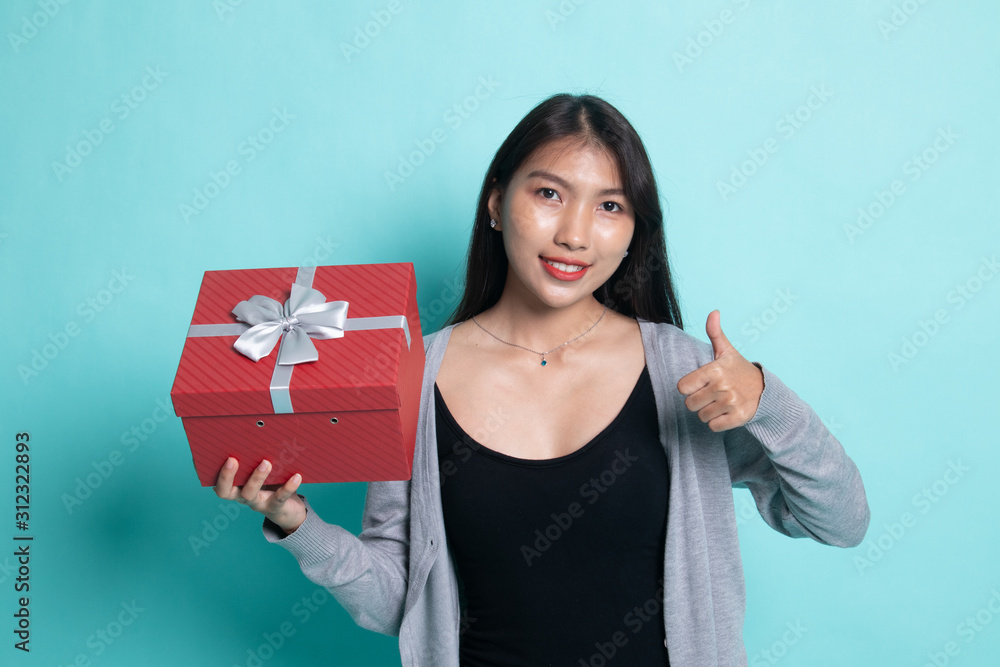 Asian woman thumbs up with a gift box. Asian woman thumbs up with a gift box.