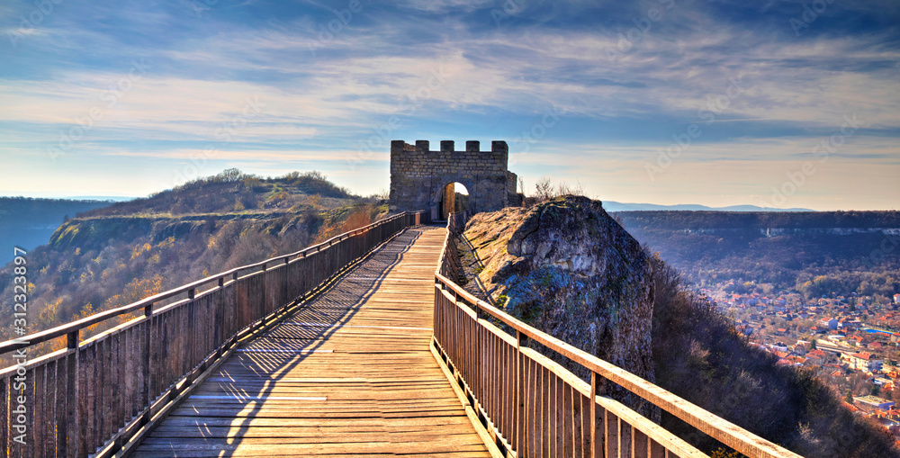 Beautiful view with wooden bridge leading to a stone gate of an ancient fortress