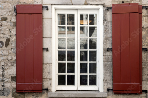 The facade of an old stone house with window and brown shutters