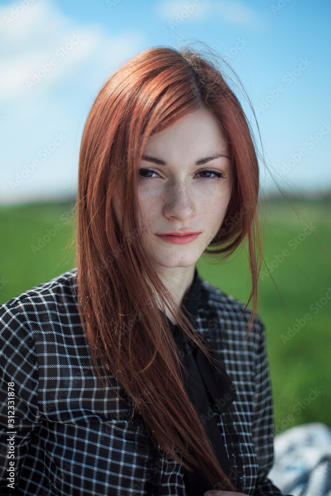 The girl with the field on a background. Freckled girl. The girl is dressed in an old dress in a section.