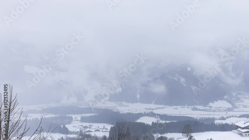 Panning time lapse shot overlooking the Austrian valley of Mittersil as seen from the hight of Pass Thurn, a famous mountain pass, on a windy and cold winter day with heavy snow fall.