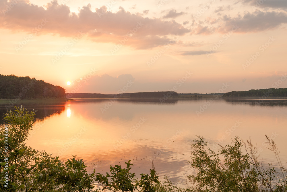 Sunset over tranquil waters of picturesque lake surrounded by forest in Zhytomyr region, Ukraine