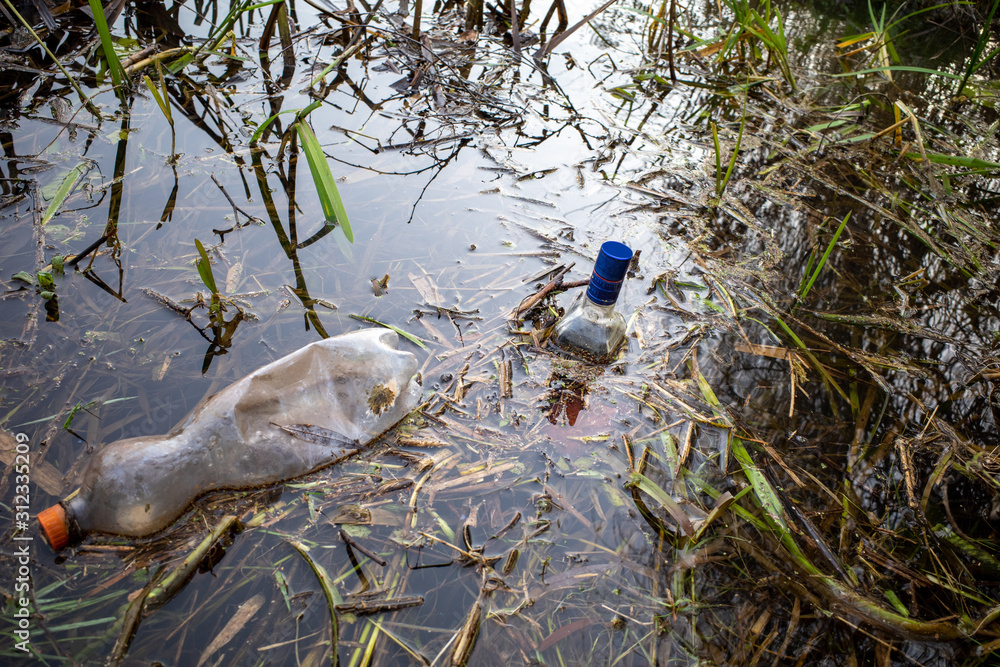 carelessly discarded plastic bottles and glass liquor bottles float in a lake carelessly discarded plastic bottles and glass liquor bottles float in a lake