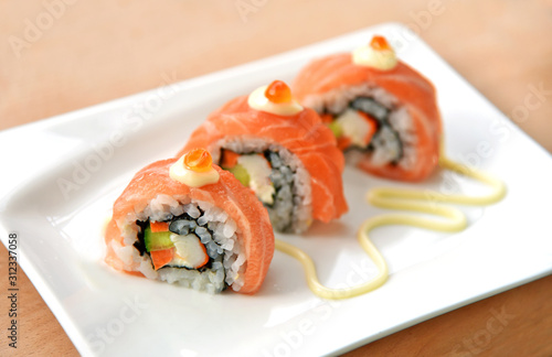 Homemade Uramaki California roll sushi with mayonnaise on white dish