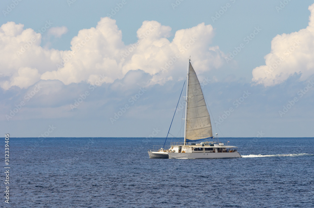 Seascape. White tourist yacht in turquoise water near a tropical island. Catamaran sailing boat.