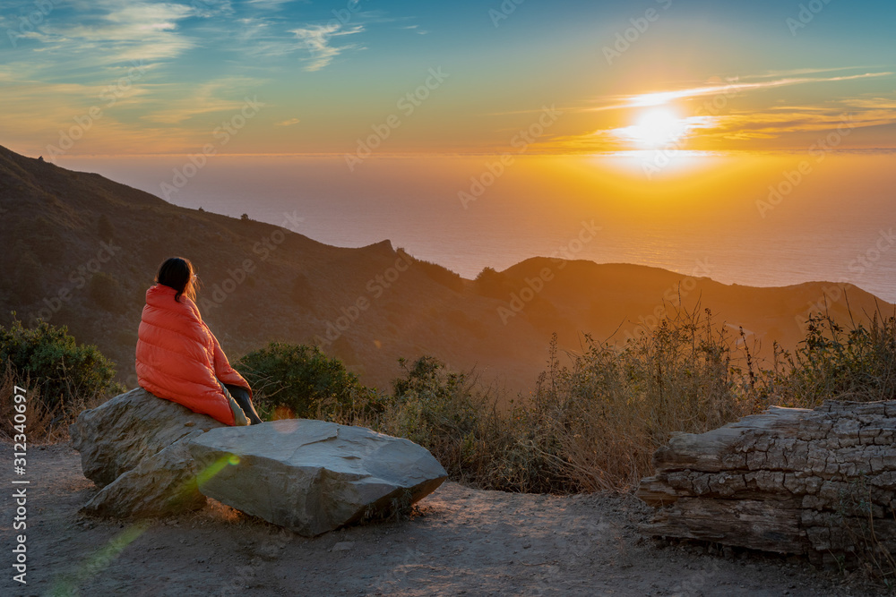Fototapeta premium Girl Wrapped in Blanket while watching sunset