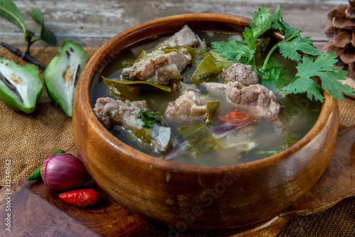 Pork spare rip Madan soup (Kra Dook Moo Tom Ma-Dun) in a wooden bowl, Traditional Thai food.