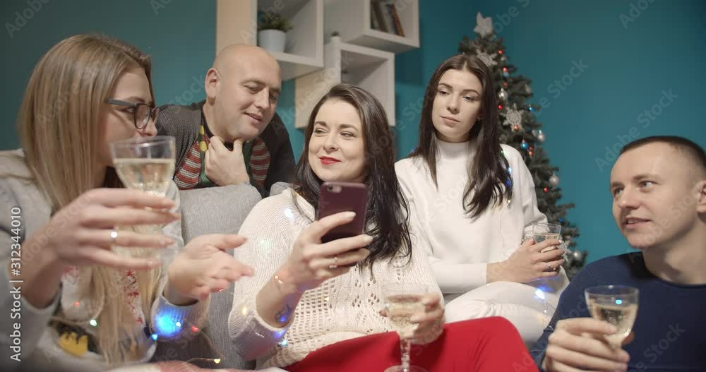 Group of male and female friends sitting on cozy couch, drinking wine and having nice chat during new year party, togetherness Group of male and female friends sitting on cozy couch, drinking wine and having nice chat during new year party, togetherness