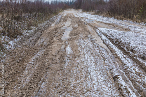 The bad ground or soil rural or suburb winter road or way with ice, snow, puddles, pools, mud and slush