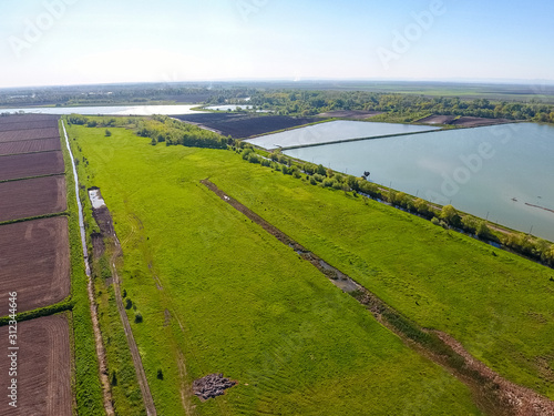 Rural landscape. View from above. On the horizon there is a fish hatchery, a field, forest belts and a river. Roads in the fields.